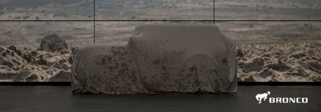 2020 Ford Bronco concealed under sheet with rocky background and bronco logo