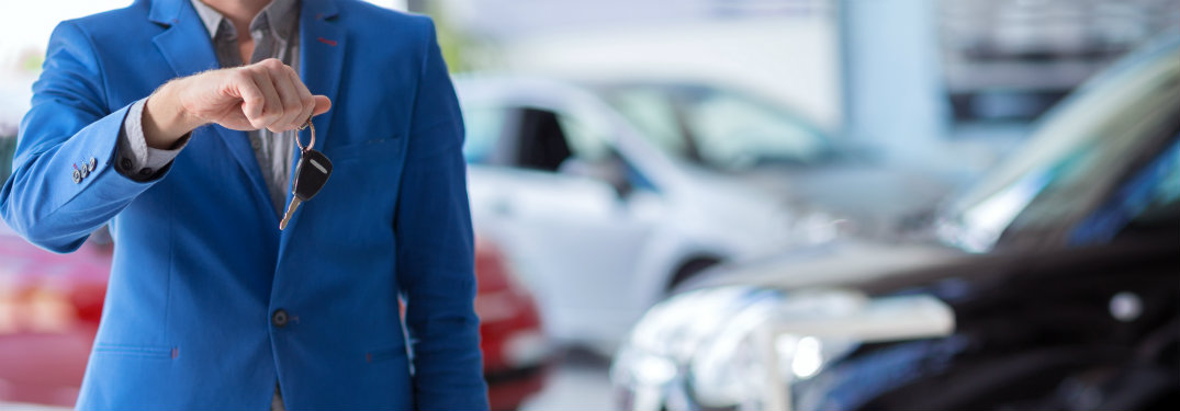 man in blue suit holding car keys