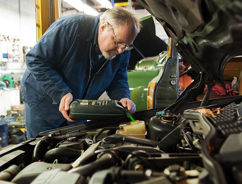 A mechanic pouring coolant in to radiator resiviour.
