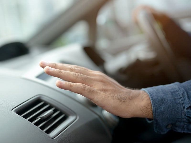 Hand over car air vent.